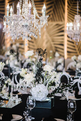 Festive decor with flower composition, candles on black tablecloth. Banquet decoration in hall restaurant. Wedding setup, dinner table reception in area on party. Setting. Birthday, baptism, event.