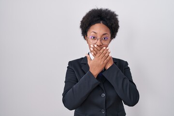 Fototapeta na wymiar Beautiful african woman with curly hair wearing business jacket and glasses shocked covering mouth with hands for mistake. secret concept.