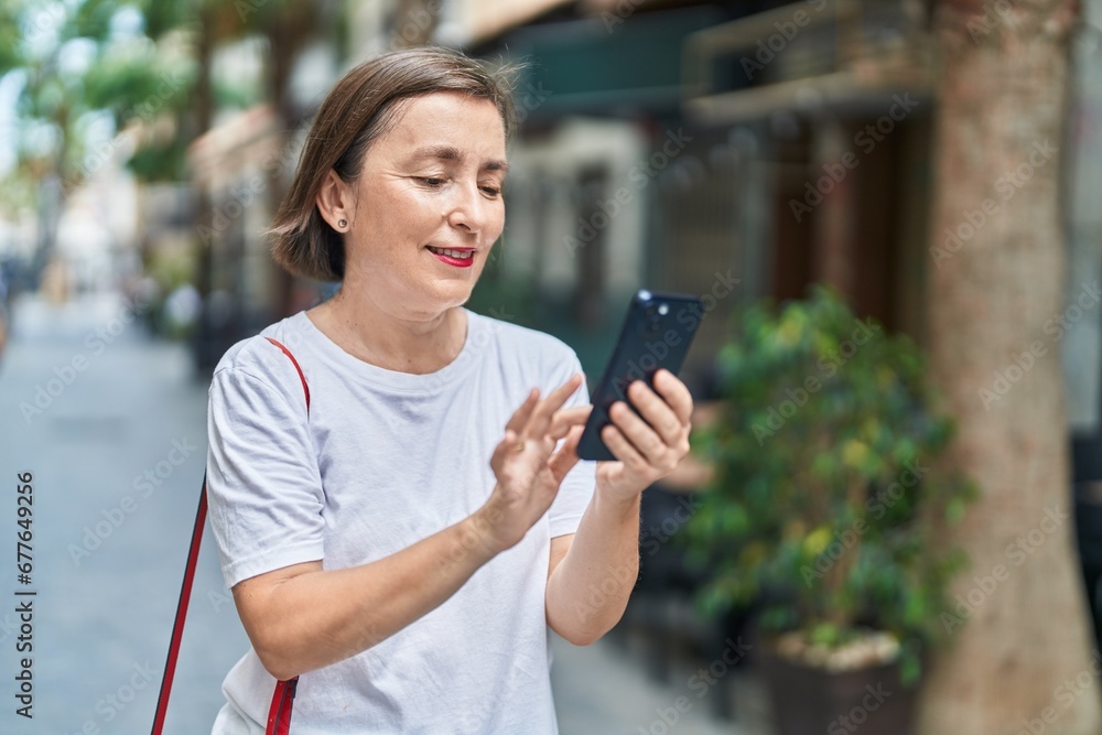 Poster Middle age woman smiling confident using smartphone at street