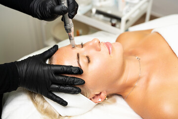 Microneedle RF lifting procedure. A cosmetologist performs a facial rejuvenation procedure on a...