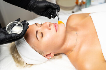 The cosmetologist from above applies a mask to the client, makes procedures in the spa or salon...