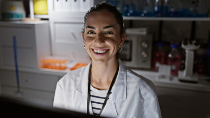 Confident and beautiful young hispanic female scientist, smiling exuberantly while immersed in groundbreaking medical research, works assiduously under soft laboratory lights