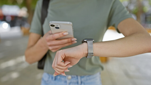Outdoor shot, woman's hands caught texting time countdown on smartphone watch at park amidst city bustle