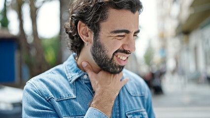 Fototapeta premium Young hispanic man suffering for throat pain at street