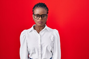 Obraz premium African woman with braids standing over red background skeptic and nervous, frowning upset because of problem. negative person.
