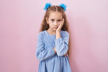 Young little girl standing over pink background thinking looking tired and bored with depression problems with crossed arms.