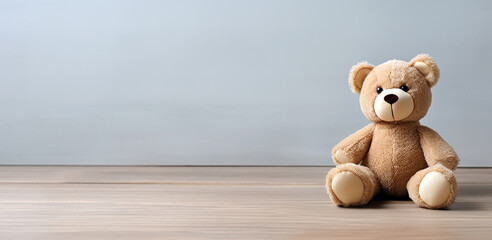 A funny teddy bear on the floor of a room sitting beside the wall. Simple, minimalist photograph, template with large copyspace.