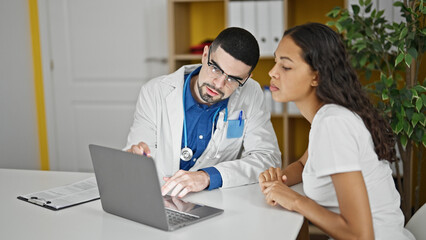 Doctor and patient engrossed in serious conversation using laptop at clinic