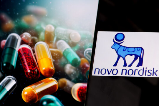 Novo Nordisk logo on phone screen, drug pills in the background, Warsaw, Poland - November 13, 2023