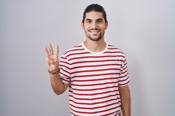 Fototapeta premium Hispanic man with long hair standing over isolated background showing and pointing up with fingers number three while smiling confident and happy.