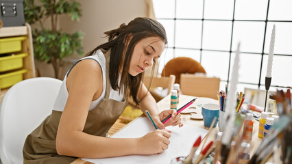 Portrait of a focused young hispanic woman, an attractive beautiful artist, engrossed in drawing...