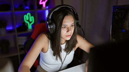 Young beautiful hispanic woman streamer playing video game using computer at gaming room