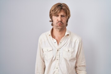 Middle age man standing over isolated background puffing cheeks with funny face. mouth inflated with air, crazy expression.