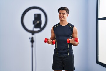 Hispanic man recording training tutorial at the gym winking looking at the camera with sexy...
