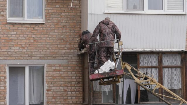 Workers are repairing the balcony of a multi-storey apartment
