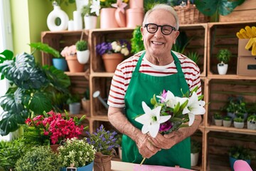 Middle age grey-haired man florist holding bouquet of flowers at flower shop