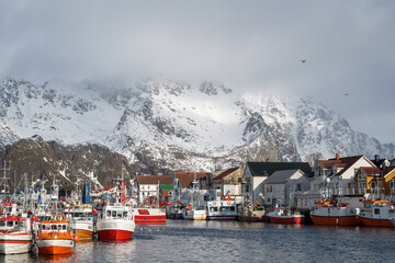 Fishing village close to snow capped mountains. Photograph of Henningsvær harbor in the Lofoten...