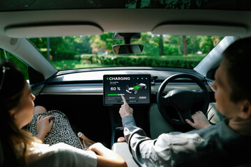 Electric car driver checks battery charging status, range and charging limit on app screen in the car. Smart technology device show EV car recharging data of electric storage in car battery innards.