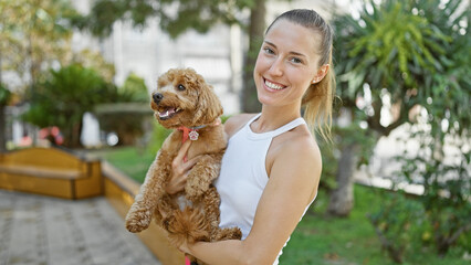 Young caucasian woman with dog smiling hugging at park