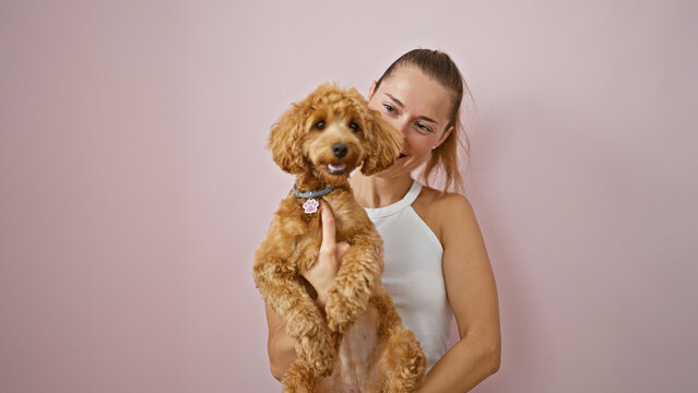 Young caucasian woman with dog smiling hugging over isolated pink background