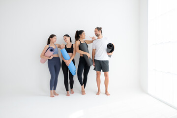Fototapeta premium A group of female and male athletes stood and chatted amicably in the studio before beginning with the yoga class.