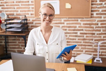 Young blonde woman business worker using laptop and touchpad at office