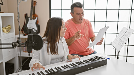 Smiling man and woman musicians engrossed in their music studio lesson, harmonizing melodies on acoustic piano while singing together