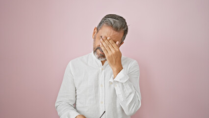 Young isolated hispanic man with grey-hair standing over pink background, visibly upset &...