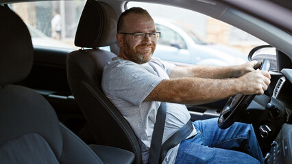Confident, smiling caucasian man celebrating a win, driving his car on a sunny urban street,...