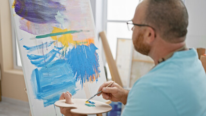 Handsome middle-aged caucasian man, an artist deeply concentrating as he passionately draws a...