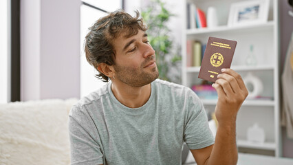Delighted young man, a beaming passport holder passes the day in his cozy home, joyously sitting on...