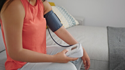 Obraz premium Young chinese woman measuring pulse using tensiometer at home