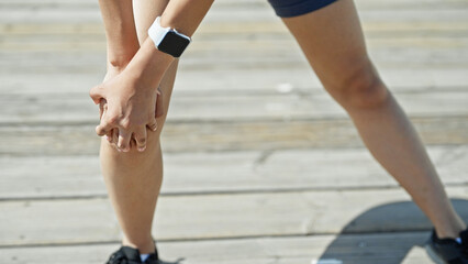 Young beautiful hispanic woman wearing sportswear suffering for knee pain at street