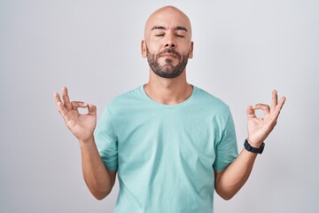 Middle age bald man standing over white background relaxed and smiling with eyes closed doing meditation gesture with fingers. yoga concept.