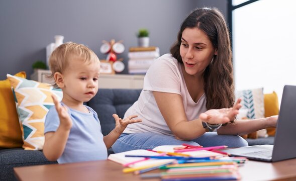 Mother and son drawing on notebook using laptop at home