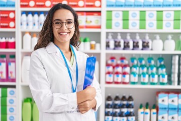 Young beautiful hispanic woman pharmacist smiling confident holding clipboard at pharmacy