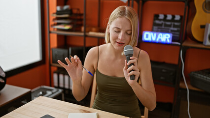 Young blonde woman musician singing song at music studio
