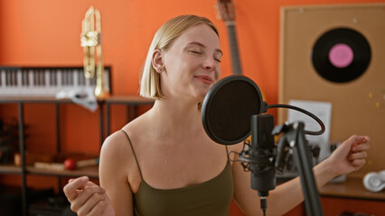 Fototapeta premium Young blonde woman musician singing song dancing at music studio