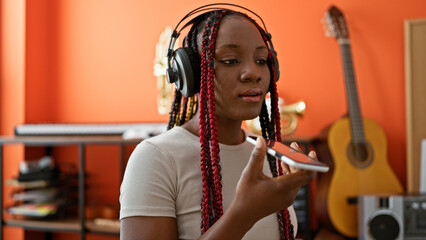 In the heart of the music studio, beautiful african american woman musician belts out a song while holding her smartphone