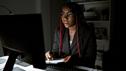 Working night magic, african american business woman rocks it at the office, taking notes and...