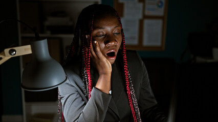 Tired, overworked african american woman business worker pulling late night shift at office,...