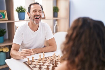 Man and woman smiling confident playing chess game at home