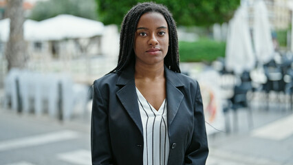 African american woman business worker standing with relaxed expression at coffee shop terrace