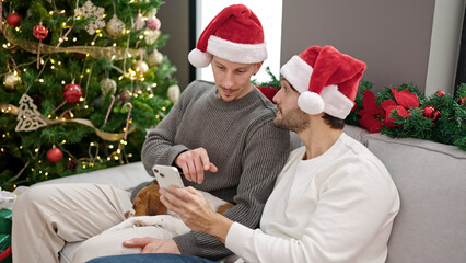 Two men couple celebrating christmas using smartphone at home