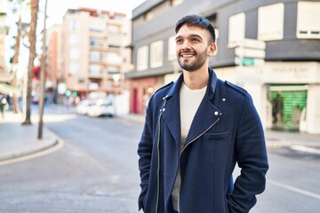 Young hispanic man smiling confident looking to the side at street