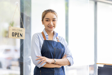 Happy SME business barista cafe owner Asian woman waitress apron and staning at the door with a...