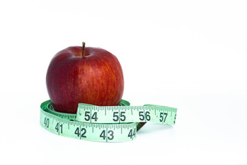 Red apple with green measuring tape on white background.