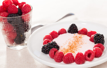 Breakfast of raspberries and blackberries with yogurt on table