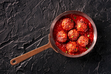 Meatballs. Beef meat balls, shot from above in a pan, with parsley and tomato sauce, on a black...