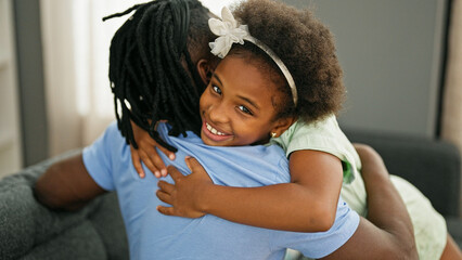 African american father and daughter smiling confident hugging each other sitting on sofa at home